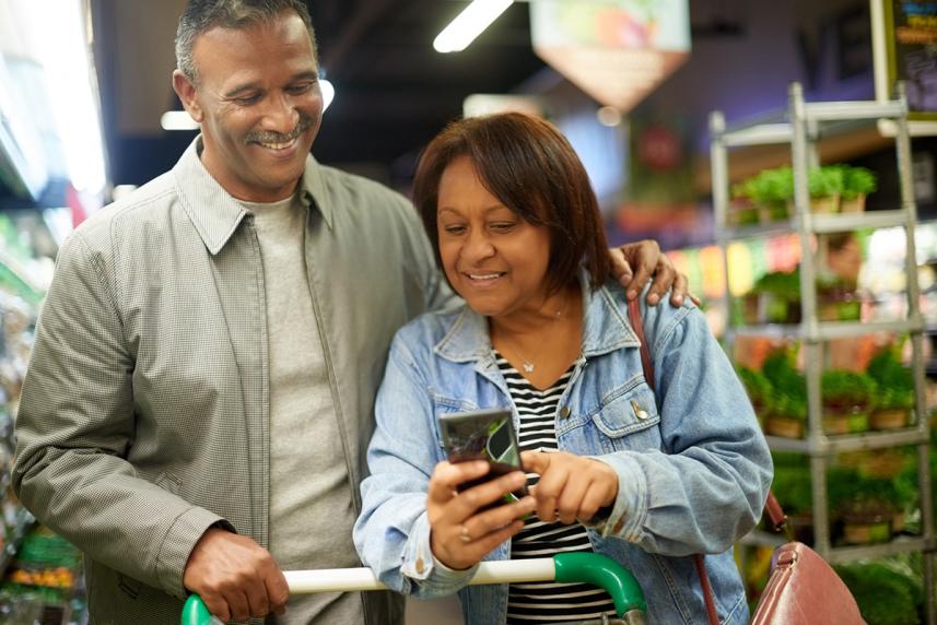 A couple shopping at a store, both looking at the phone in the woman's hand