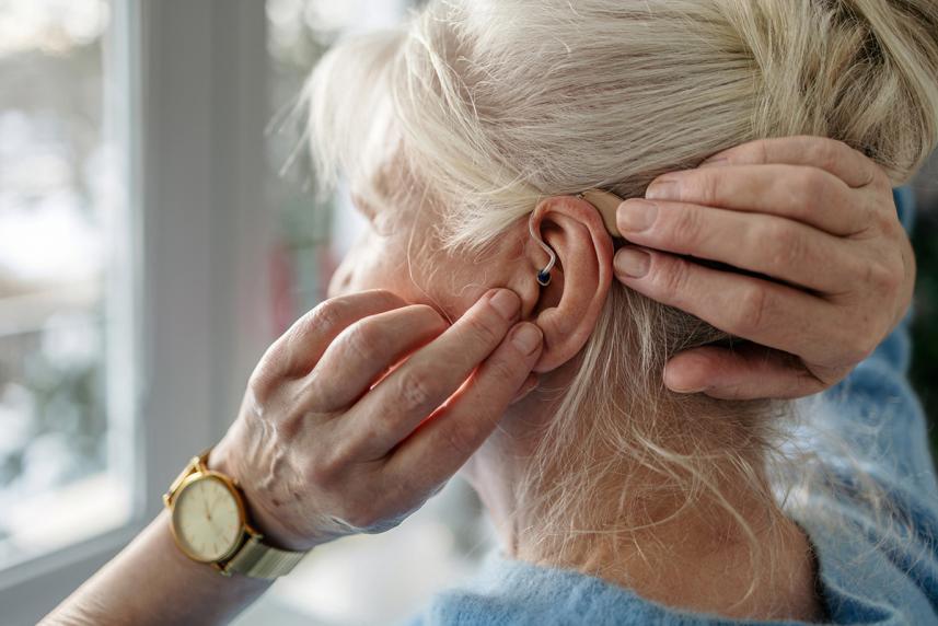 A woman touching the hearing aid in her ear