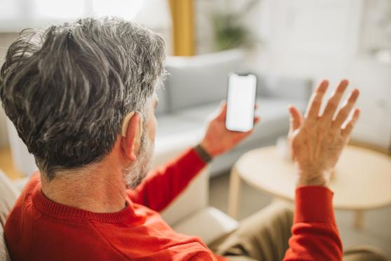 Man with a hearing aid looking at a phone